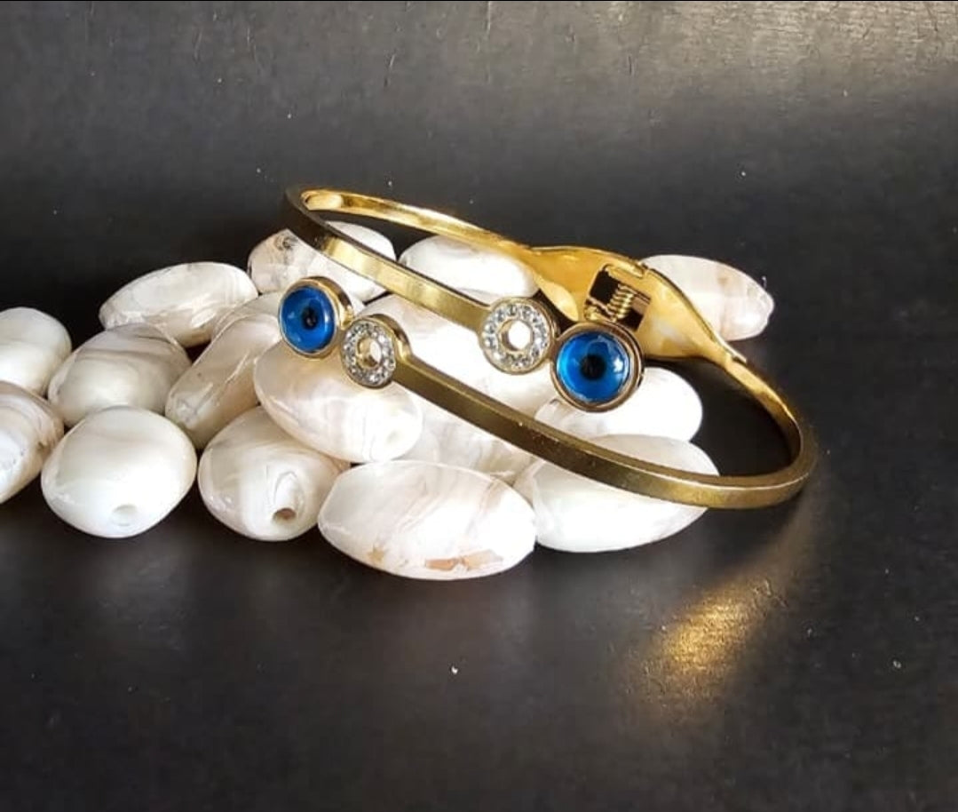 Gold bracelet with blue and clear gemstones on white stones against a dark background