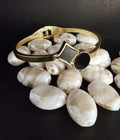 Gold bracelet with a black gemstone on a dark surface with white stones