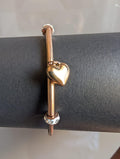 Gold bracelet with a heart charm on a gray surface
