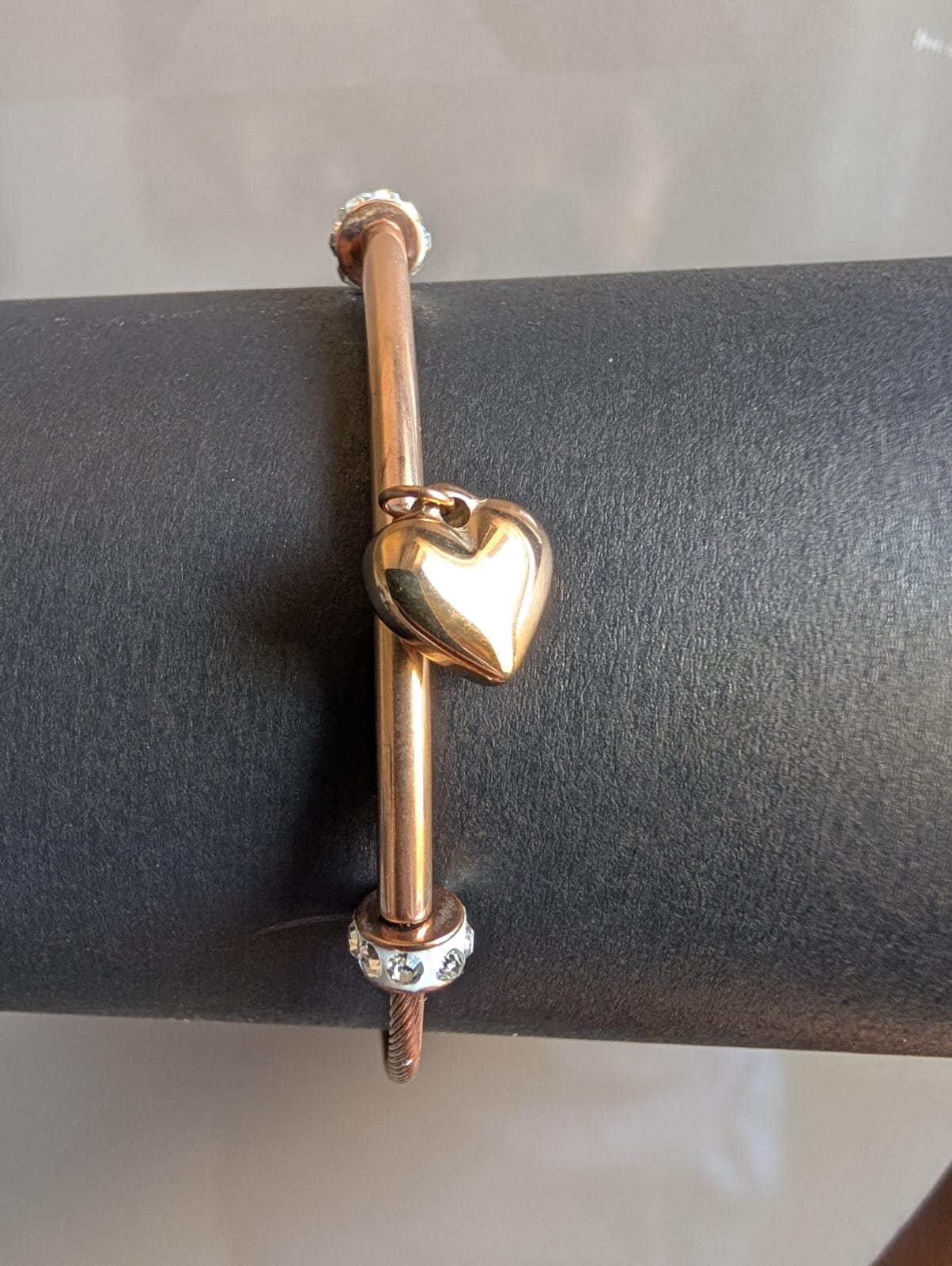 Gold bracelet with a heart charm on a gray surface
