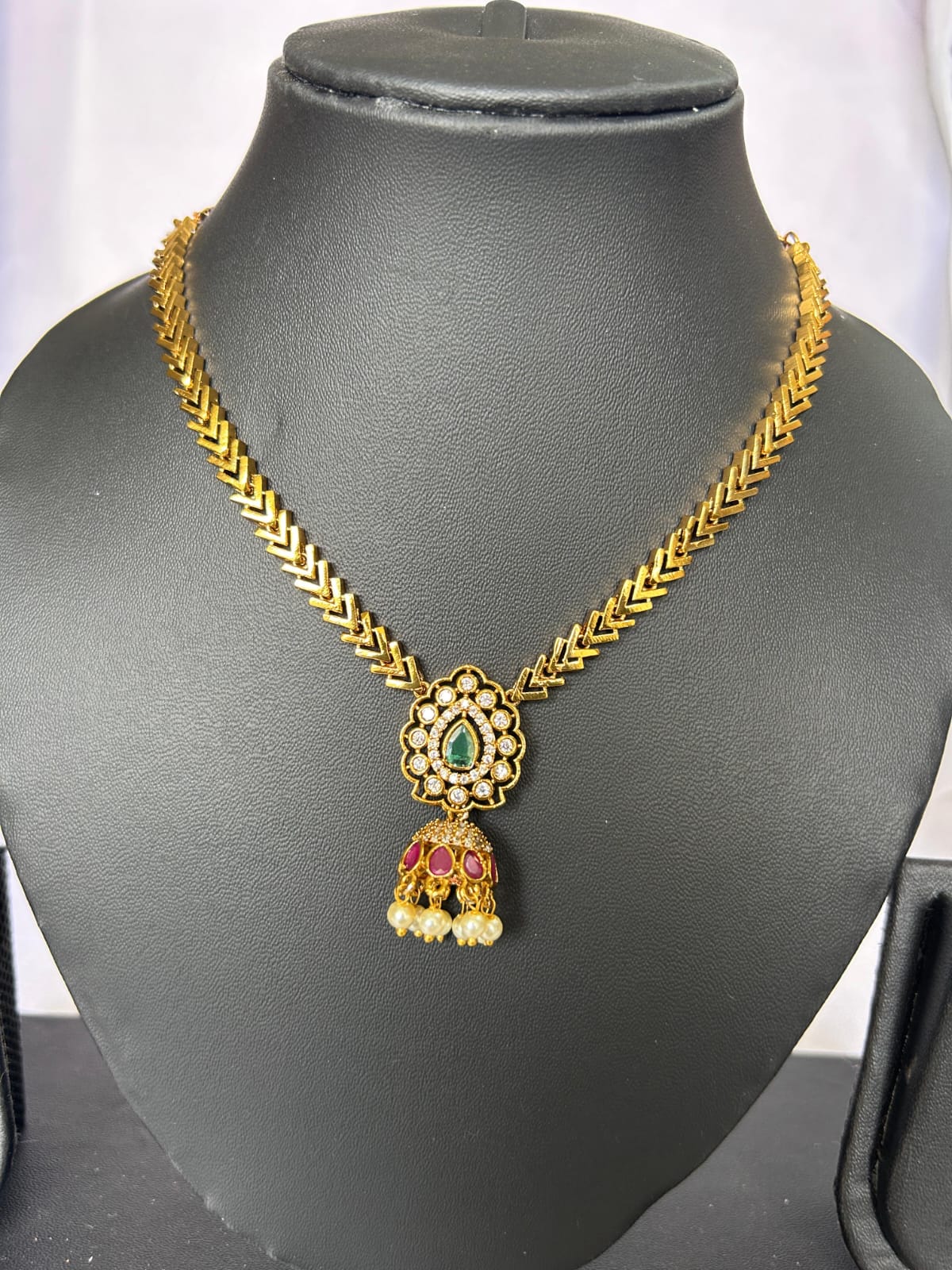 Gold necklace with a pendant on a black mannequin