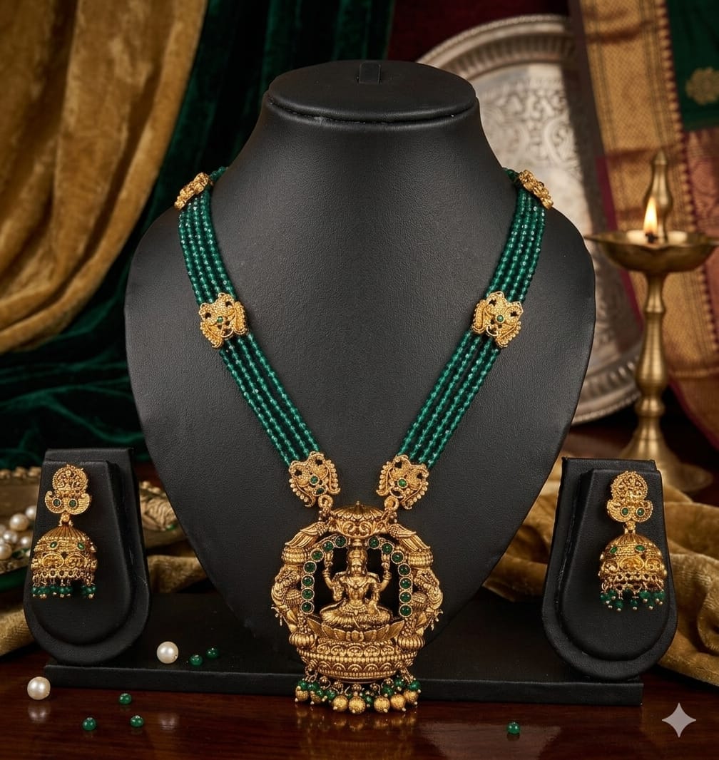 Gold and green necklace set on a black mannequin with matching earrings.