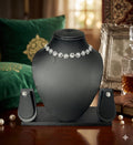 Black mannequin bust with diamond necklace and earrings on a wooden surface.