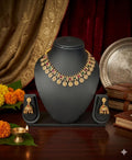 Gold necklace and earrings on a black stand with decorative background