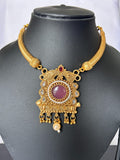 Gold necklace with a purple gemstone on a black mannequin