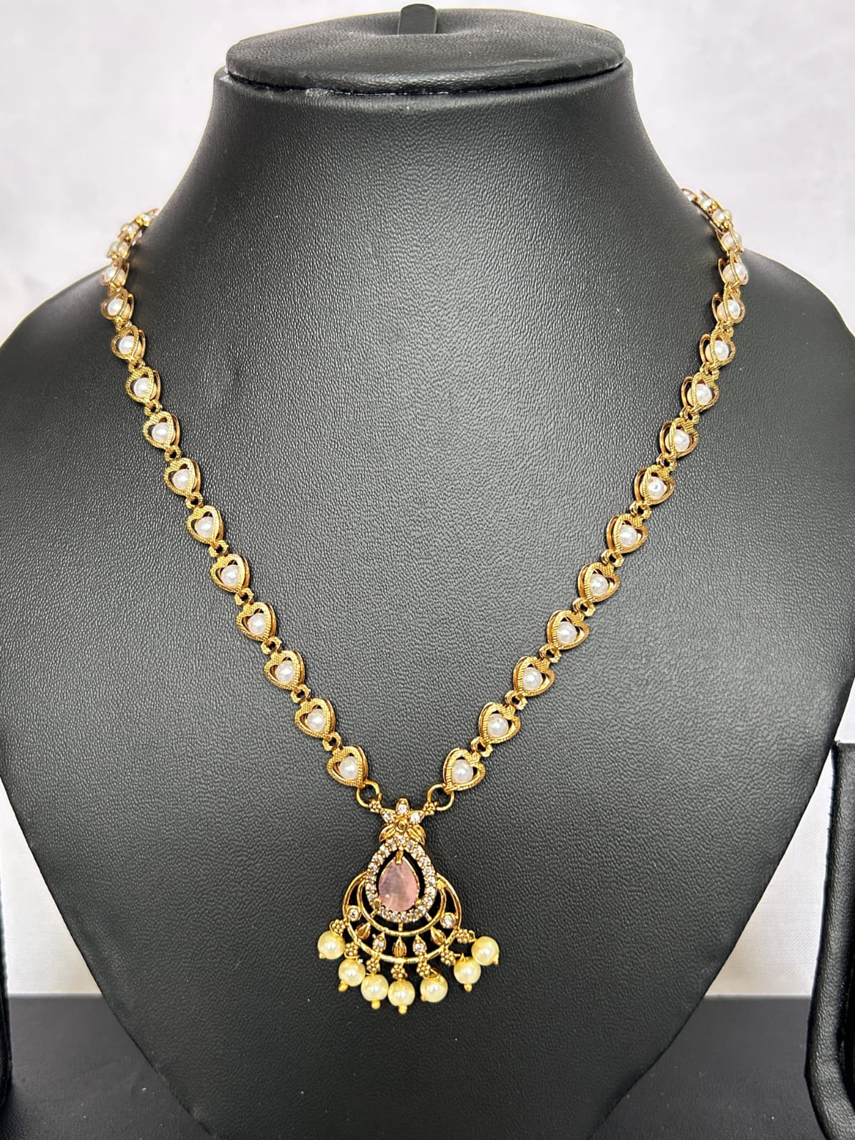 Gold necklace with a pendant on a black mannequin