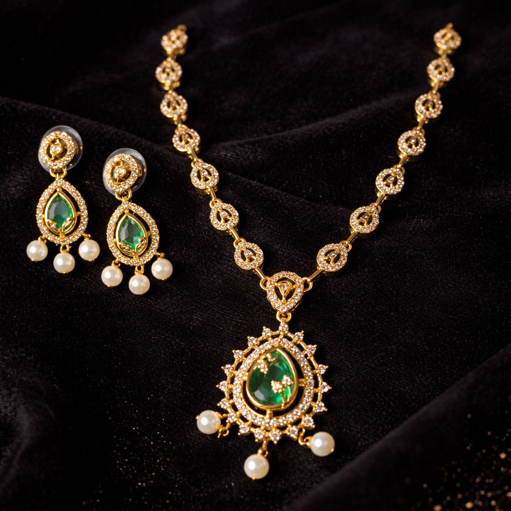 Gold necklace with green gemstones and pearl earrings on a black velvet background