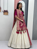 Woman in a traditional outfit with a white and red saree, standing indoors.