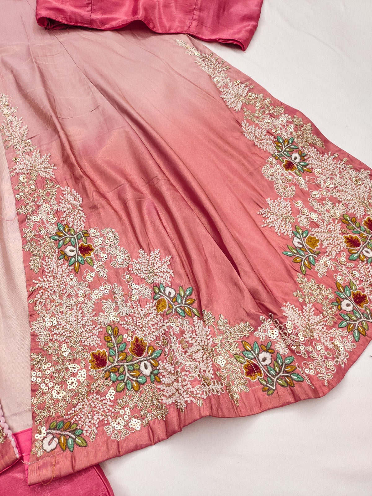 Pink fabric with intricate floral embroidery on a white background