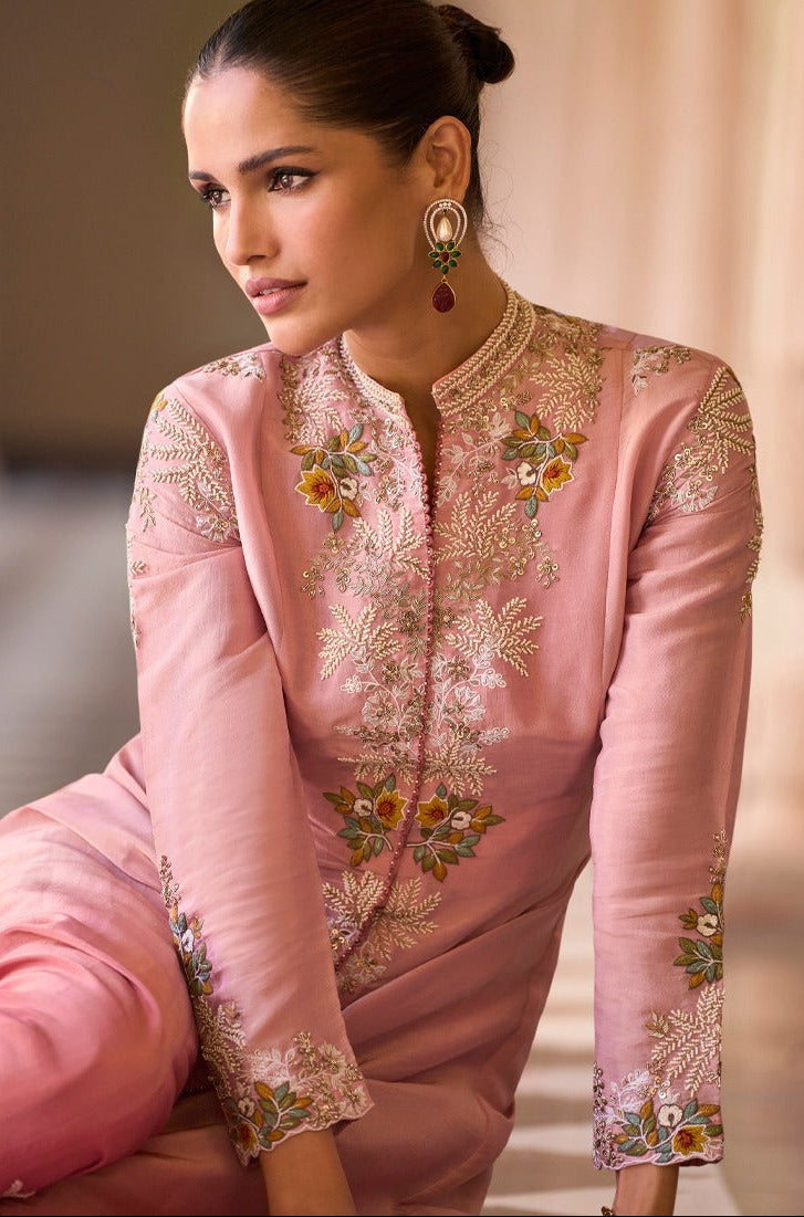 Woman wearing a pink embroidered traditional outfit with a blurred background